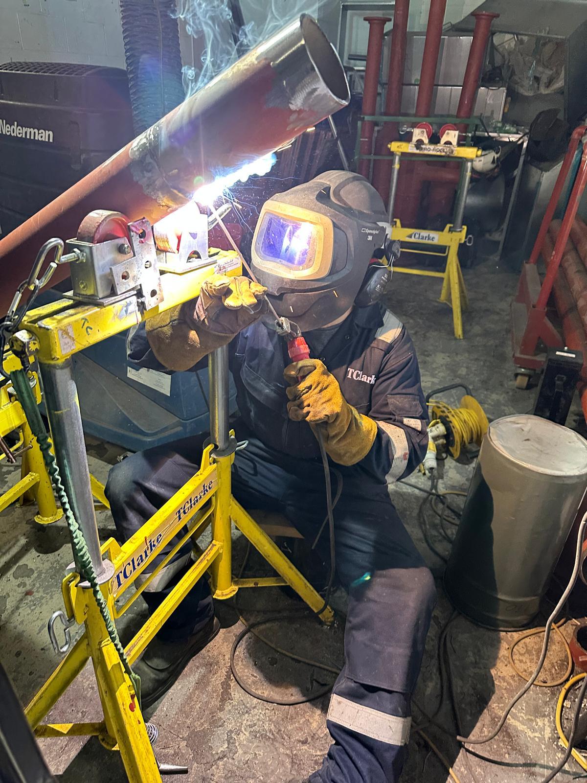 Mike welding pipe in workshop with full PPE